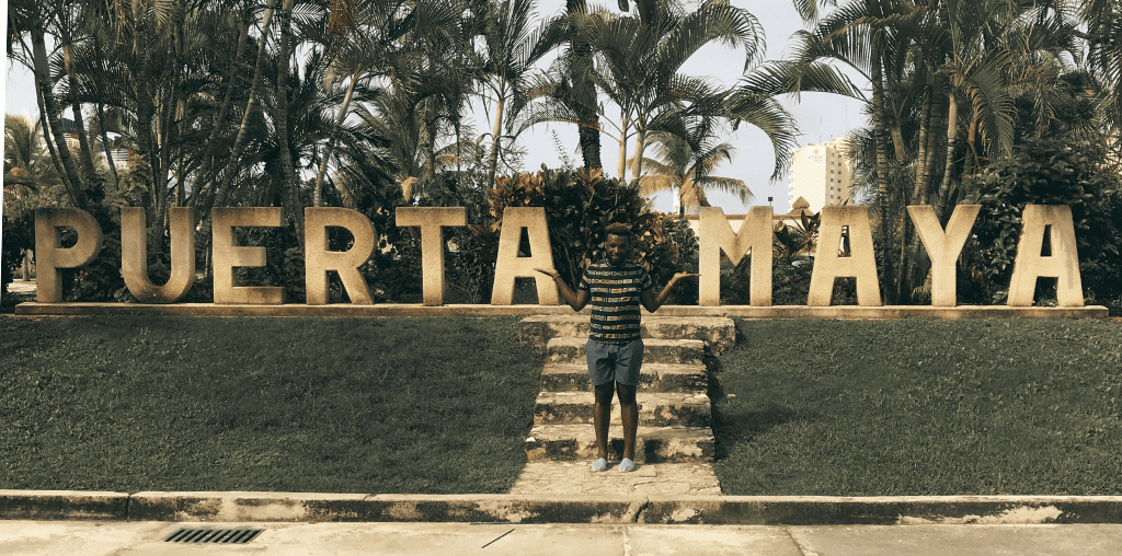 Paris Jones stands in front of a sign in Puerta Maya, his favorite destination during his time as a flight attendant.